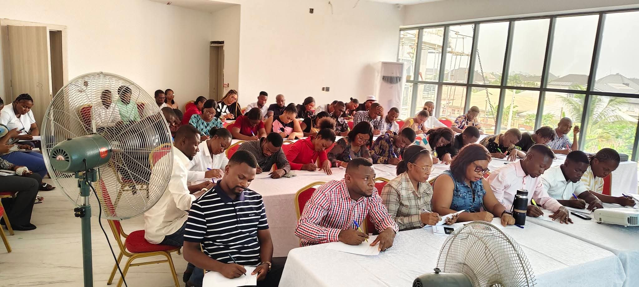 A full training room of participants writing at long tables during a Reginel session